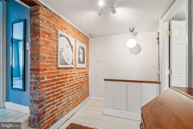 hall featuring baseboards, brick wall, and hardwood / wood-style flooring