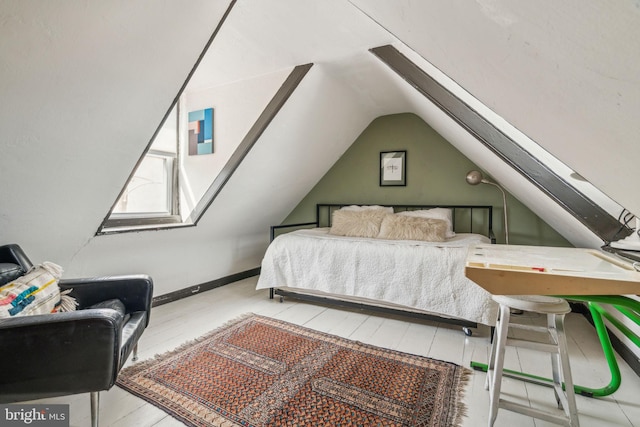 bedroom featuring lofted ceiling, baseboards, and wood finished floors