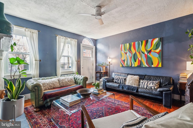 living room with a textured ceiling, a ceiling fan, and wood finished floors