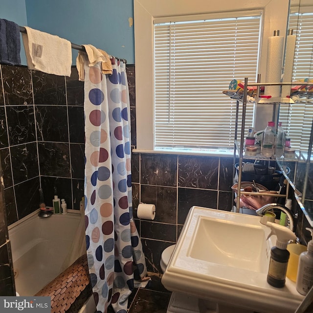 full bath with a shower with curtain, wainscoting, a sink, and tile walls