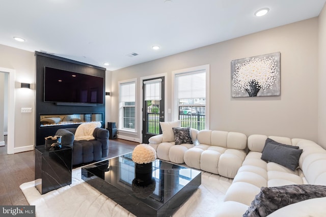 living room with recessed lighting, visible vents, a large fireplace, wood finished floors, and baseboards