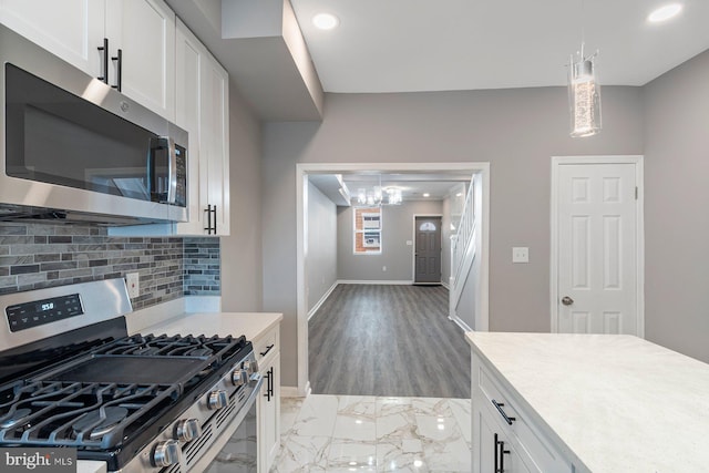 kitchen with baseboards, appliances with stainless steel finishes, light countertops, white cabinetry, and backsplash