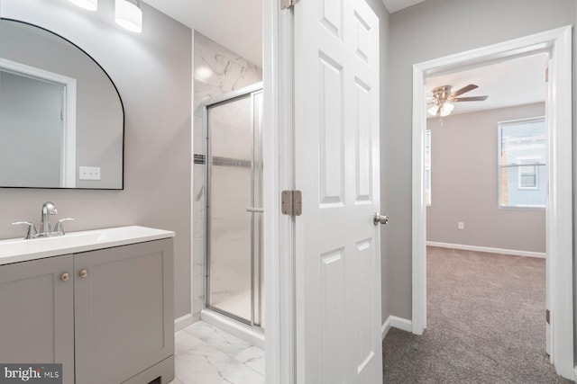 bathroom with marble finish floor, baseboards, a shower stall, and vanity