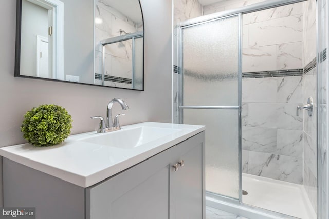 full bathroom with marble finish floor, a stall shower, and vanity