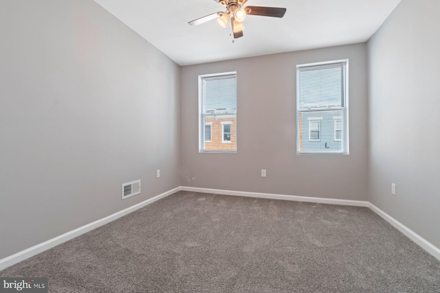 carpeted empty room featuring ceiling fan, visible vents, and baseboards