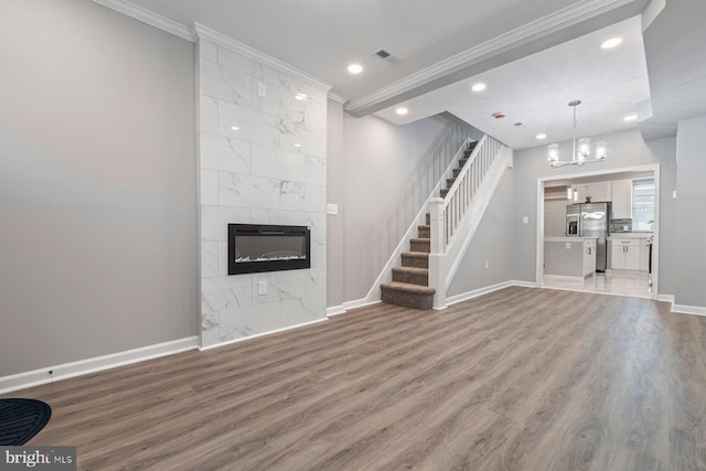 unfurnished living room with crown molding, a fireplace, visible vents, wood finished floors, and baseboards