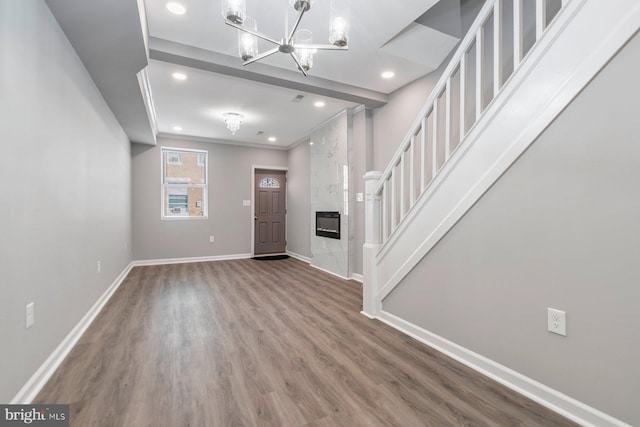 entrance foyer with baseboards, a premium fireplace, wood finished floors, an inviting chandelier, and recessed lighting