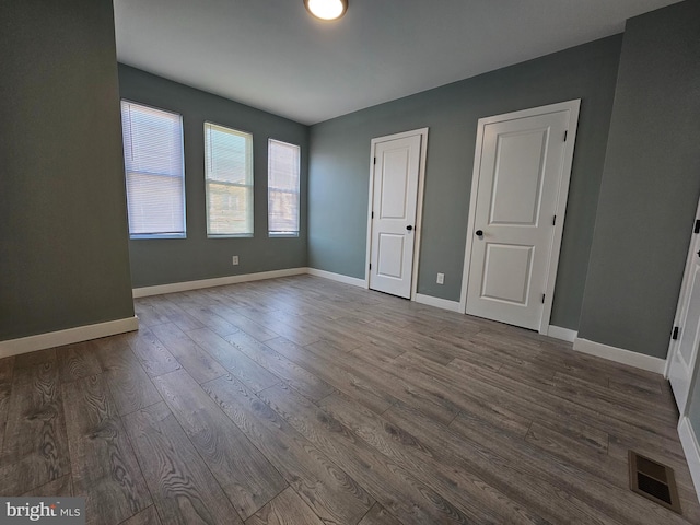 unfurnished bedroom with baseboards, visible vents, and wood finished floors