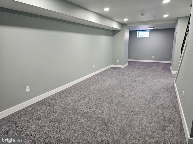 basement featuring dark colored carpet, baseboards, and recessed lighting