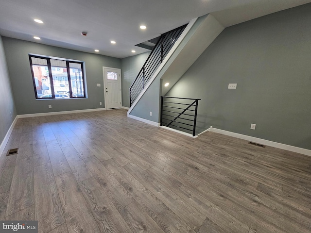 unfurnished living room featuring visible vents, baseboards, and wood finished floors