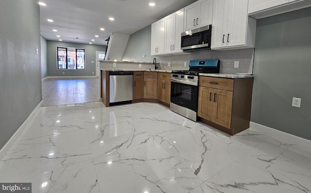 kitchen with appliances with stainless steel finishes, white cabinets, brown cabinetry, and light stone countertops