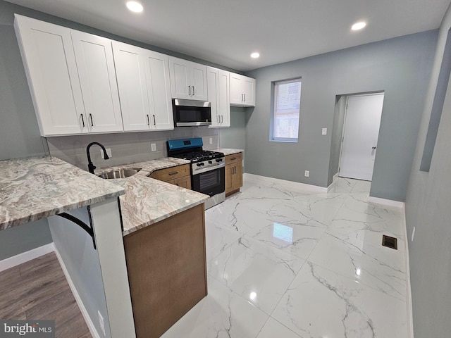 kitchen with white cabinets, light stone countertops, marble finish floor, stainless steel appliances, and a sink