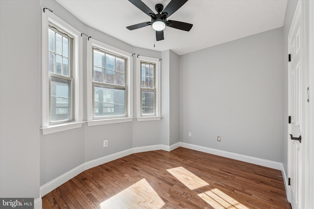 unfurnished bedroom featuring multiple windows, baseboards, wood finished floors, and a ceiling fan