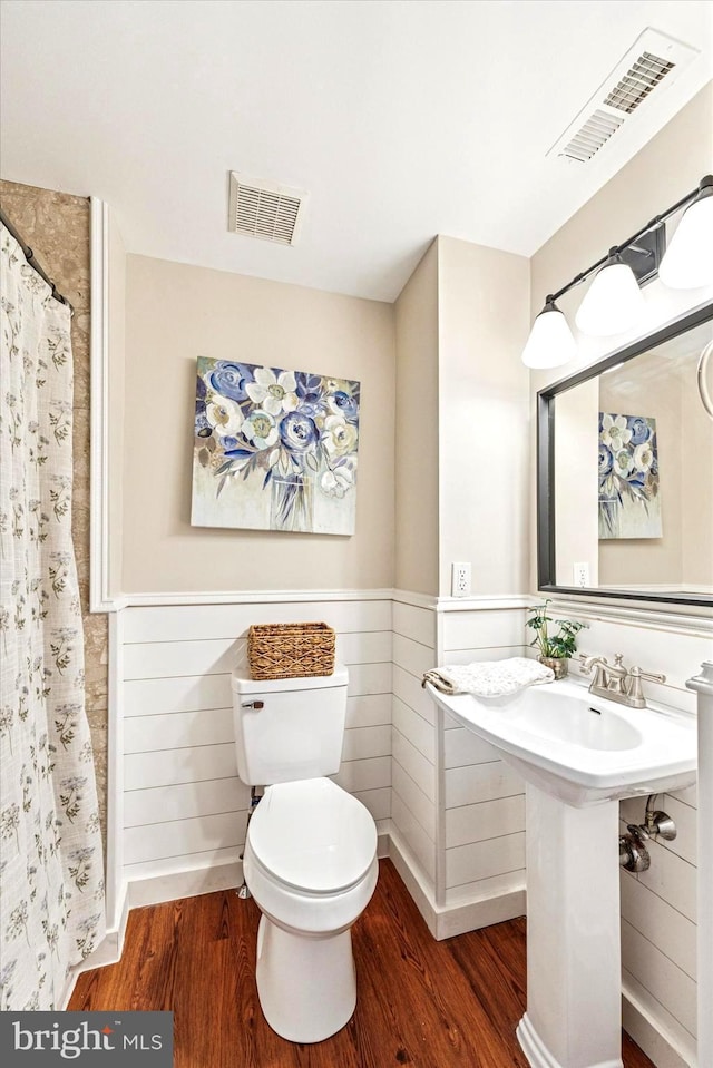 full bathroom with visible vents, toilet, wood finished floors, and a wainscoted wall