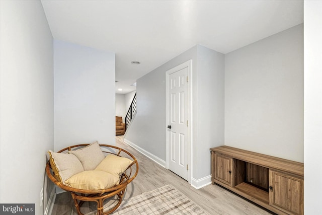 living area featuring light wood-type flooring, baseboards, and stairs