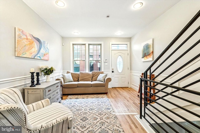 living area with recessed lighting, stairway, wainscoting, and light wood finished floors