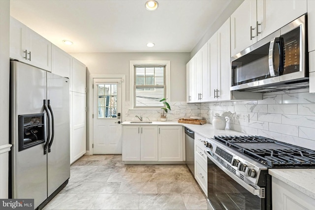 kitchen with decorative backsplash, recessed lighting, stainless steel appliances, white cabinetry, and a sink