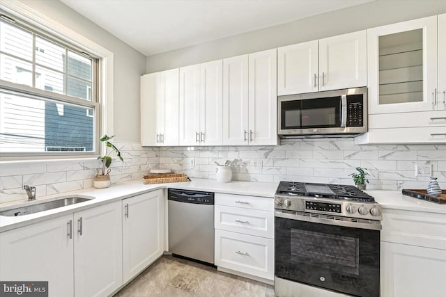 kitchen featuring a sink, decorative backsplash, light countertops, white cabinets, and stainless steel appliances