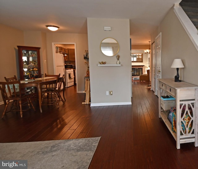 dining area featuring a fireplace, baseboards, and dark wood-type flooring