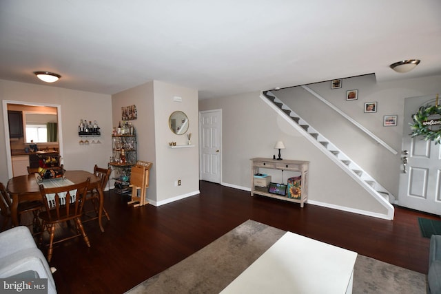 living room featuring baseboards, stairway, and dark wood-type flooring