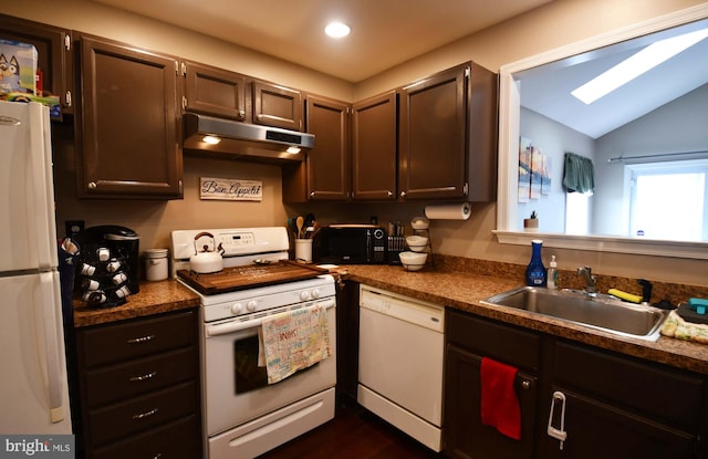 kitchen with white appliances, dark countertops, lofted ceiling, under cabinet range hood, and a sink