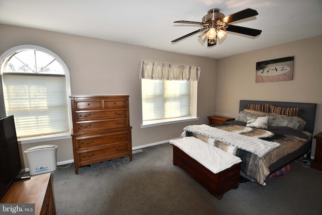 bedroom featuring multiple windows, dark carpet, and baseboards