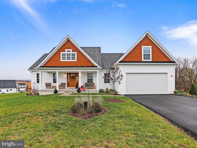 view of front of home featuring covered porch, roof with shingles, driveway, and a front lawn