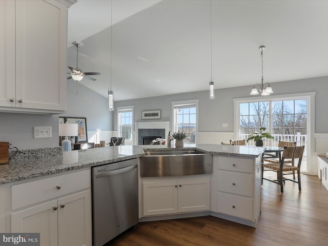 kitchen with dark wood-type flooring, light stone countertops, stainless steel dishwasher, white cabinetry, and a sink