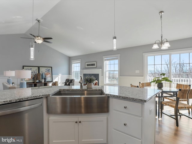 kitchen featuring open floor plan, white cabinets, dishwasher, and a sink