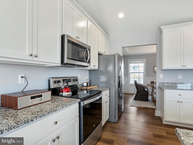 kitchen featuring appliances with stainless steel finishes, white cabinetry, light stone counters, and dark wood-style floors