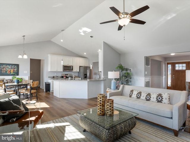 living area with ceiling fan with notable chandelier, high vaulted ceiling, dark wood-style flooring, and visible vents