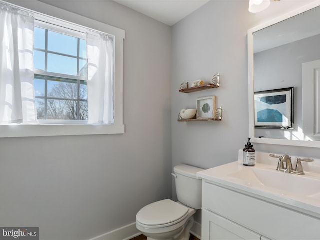 half bathroom featuring vanity, toilet, and baseboards