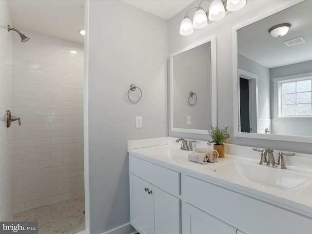 full bath with visible vents, a sink, and tiled shower