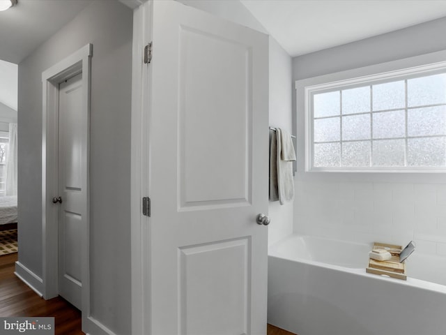 bathroom with wood finished floors, ensuite bath, a garden tub, and a healthy amount of sunlight