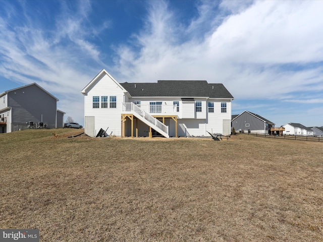 back of property with a lawn, fence, and stairs