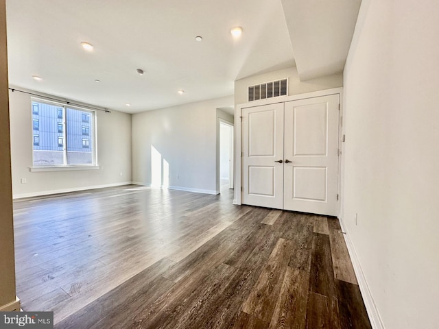 unfurnished living room featuring baseboards, visible vents, and dark wood-type flooring