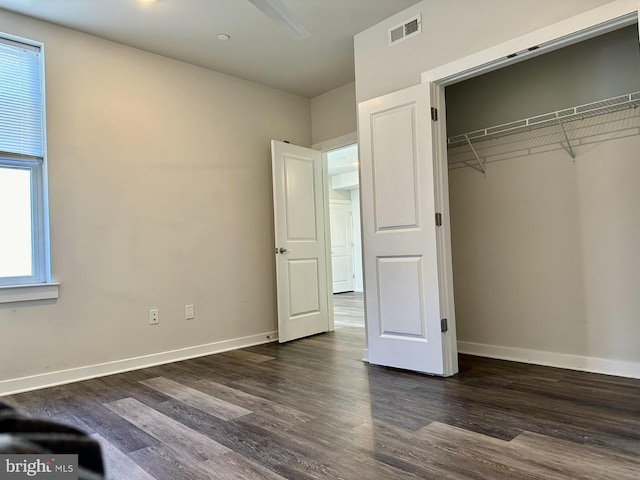 unfurnished bedroom featuring baseboards, a closet, visible vents, and dark wood-type flooring