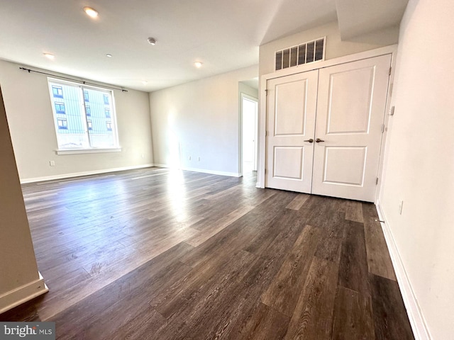 unfurnished bedroom featuring baseboards, visible vents, dark wood finished floors, and a closet