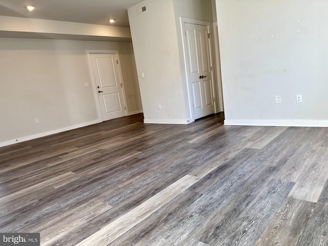 unfurnished room with dark wood-type flooring, visible vents, and baseboards