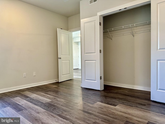 unfurnished bedroom featuring baseboards, visible vents, dark wood-style flooring, and a closet