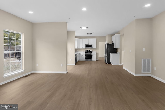 unfurnished living room featuring baseboards, visible vents, wood finished floors, and recessed lighting