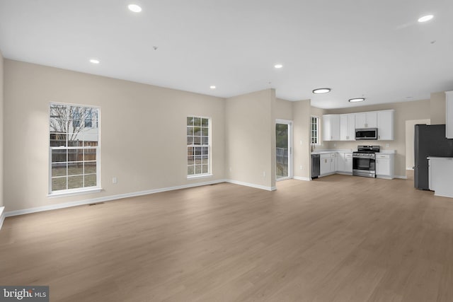 unfurnished living room featuring light wood finished floors, recessed lighting, and baseboards