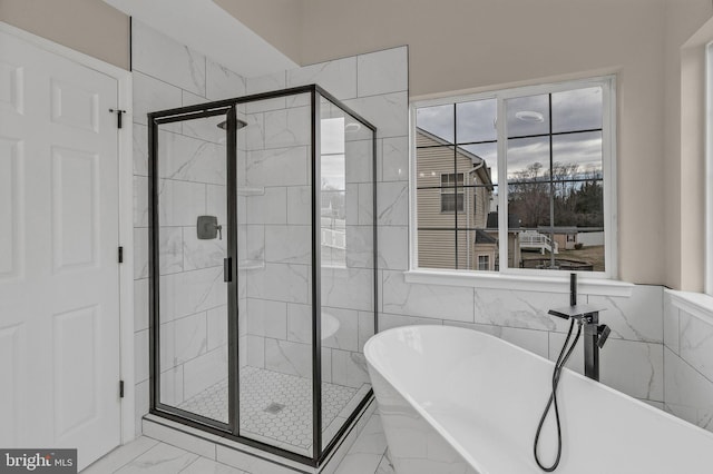 full bath with a soaking tub, marble finish floor, tile walls, and a stall shower