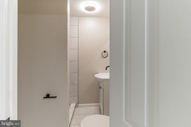 bathroom with a shower, vanity, toilet, and baseboards