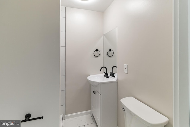 bathroom featuring toilet, marble finish floor, baseboards, and vanity