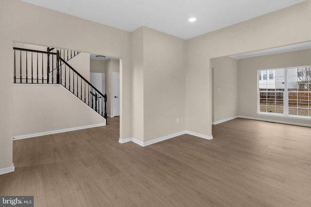 empty room with stairs, baseboards, wood finished floors, and recessed lighting