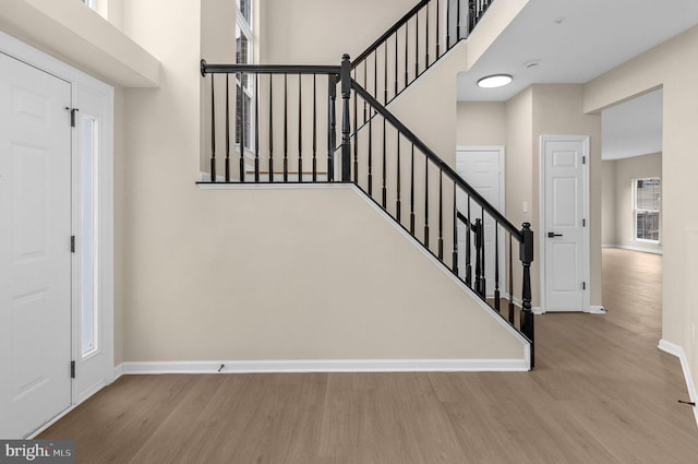 stairway with a high ceiling, baseboards, and wood finished floors