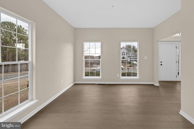 spare room with dark wood-style flooring and baseboards