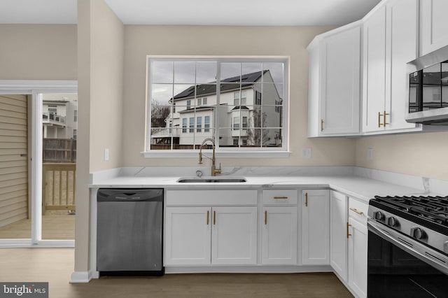 kitchen featuring a wealth of natural light, white cabinetry, appliances with stainless steel finishes, and a sink