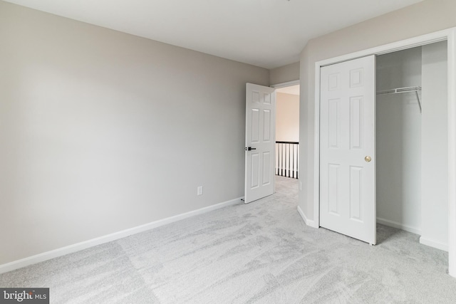 unfurnished bedroom with a closet, light carpet, and baseboards